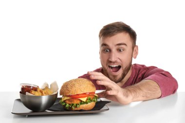 Genç adam renk arka plan üzerinde lezzetli hamburger yeme