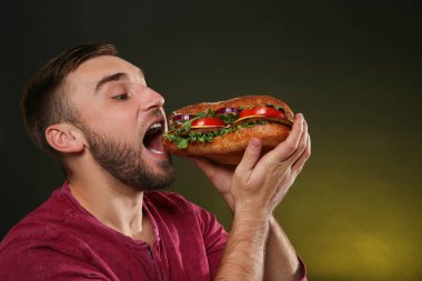 Genç adam renk arka plan üzerinde lezzetli hamburger yeme
