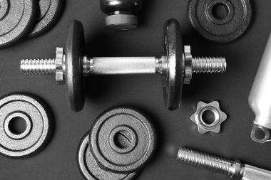 Dumbbell ve parçaları koyu arka plan üzerinde düz yatıyordu kompozisyonu