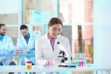 Laboratuar mikroskobu ile çalışan genç bilim adamı. Kimyasal analiz