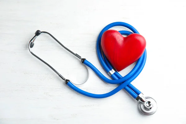 听诊器和红色的心在木制背景 顶部的看法 心脏科概念 — 图库照片