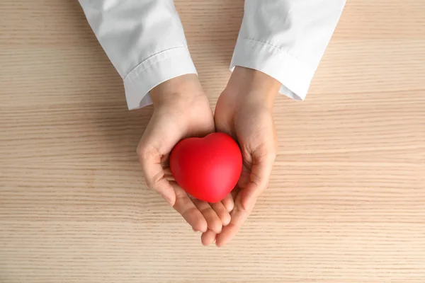 Doctor Holding Red Heart Wooden Table Top View Cardiology Concept — Stock Photo, Image