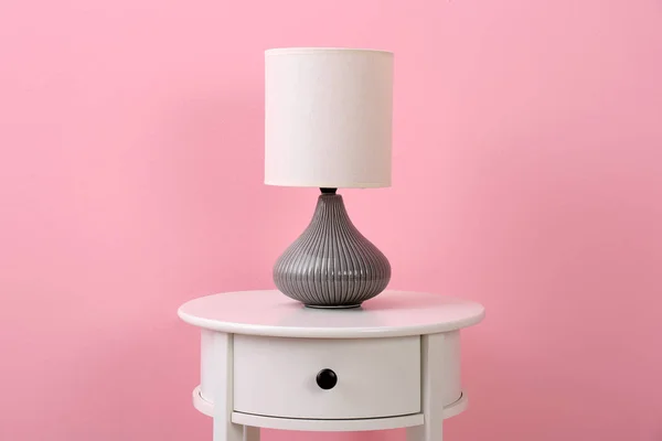 Stylish lamp on table against color background