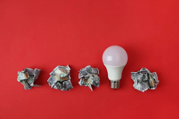 Flat lay composition with lamp bulb and crumpled money on color background
