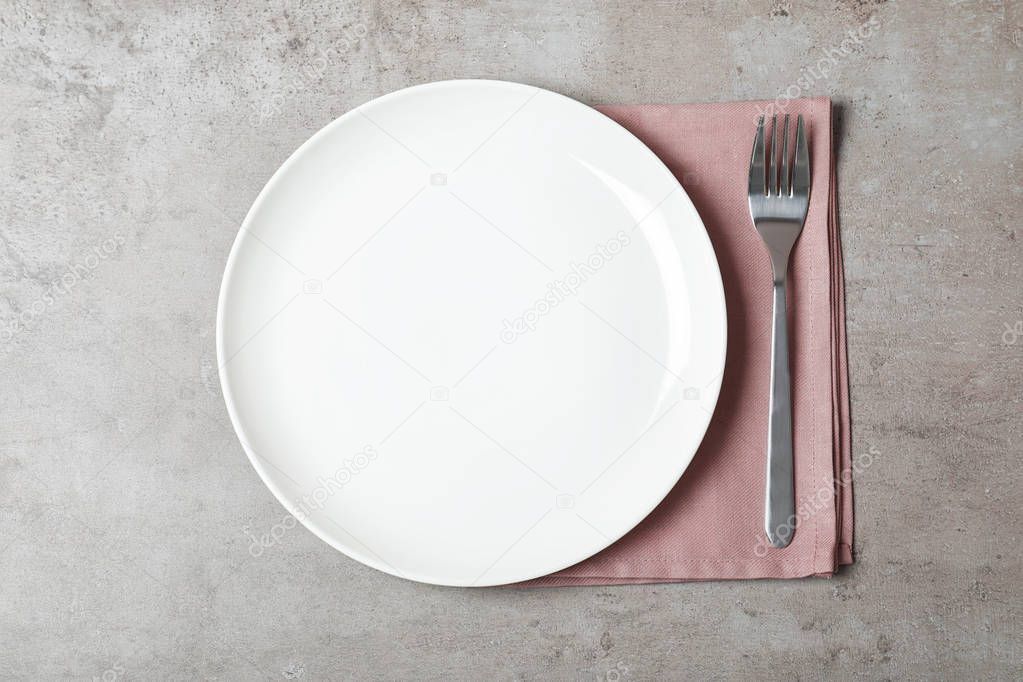 Fabric napkin with plate and fork on table, top view
