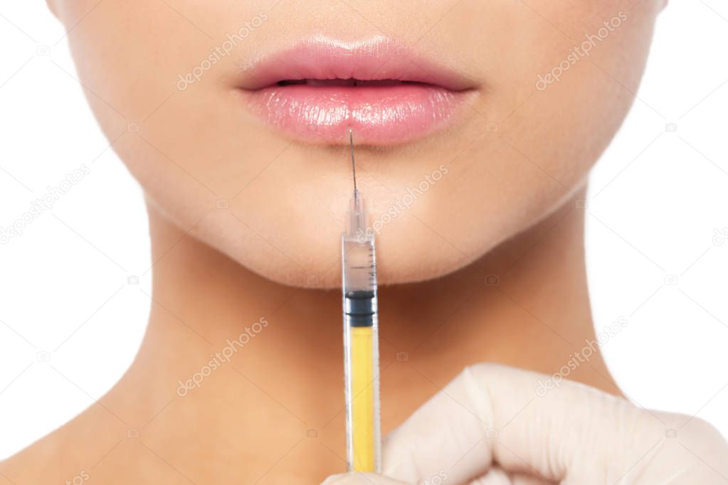 Young woman getting lips injection on white background, closeup. Cosmetic surgery