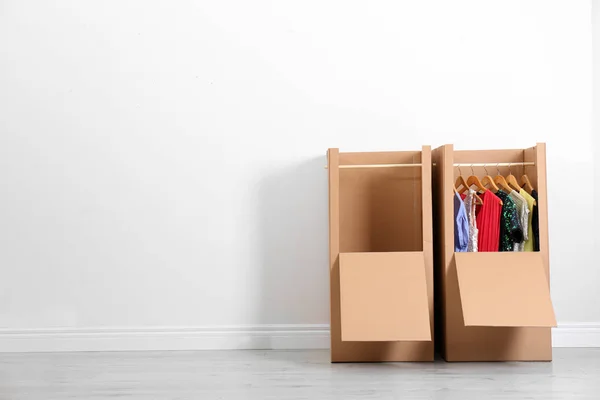 Wardrobe boxes with clothes against light wall indoors. Space for text