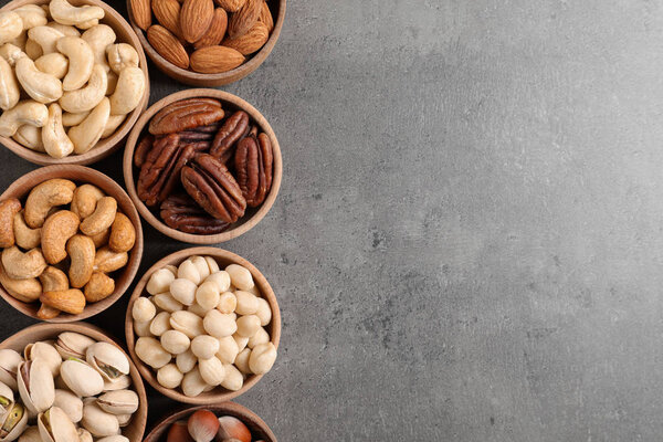 Плоская композиция с органическими орехами и пространством для текста на сером фоне, вид сверху. Снэк
