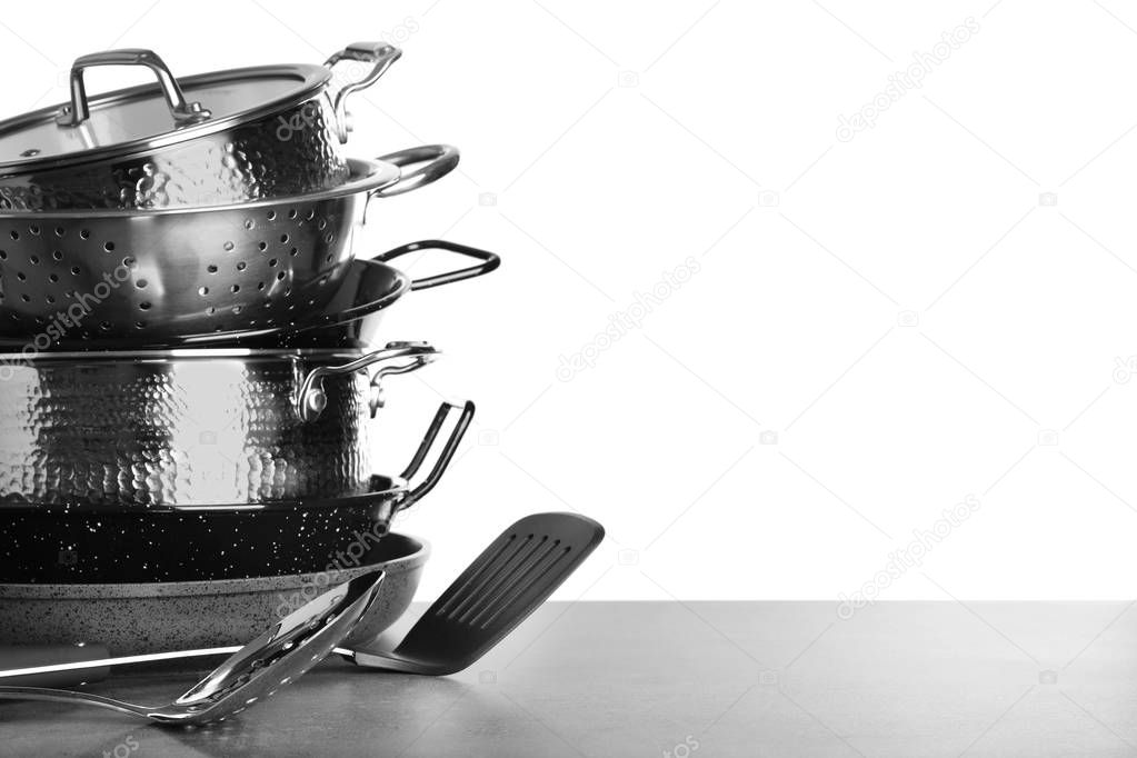 Set of clean cookware and utensils on table against white background, space for text