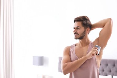 Yatak odasında deodorant uygulamak yakışıklı delikanlı. Metin için yer
