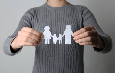 Gri arka plan üzerinde closeup aile silüeti kağıt tutan kadın. Hayat sigortası kavramı