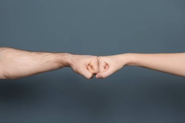 Young man and woman making fist bump on color background clipart