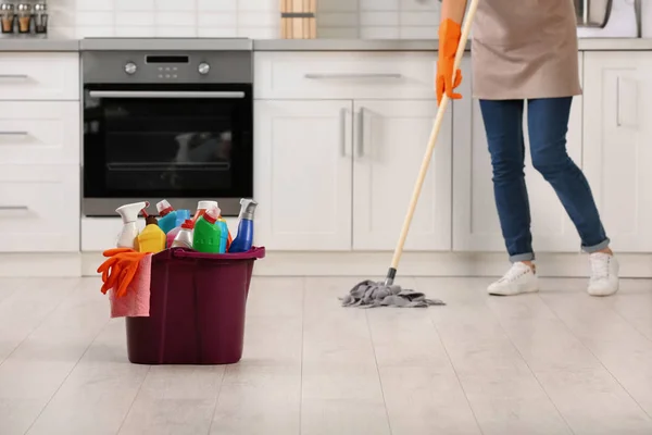 Set of cleaning supplies on floor in kitchen. Space for text