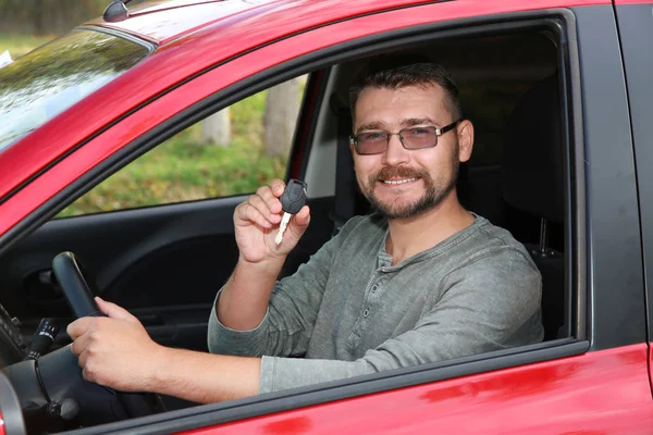 Man showing car key from new automobile
