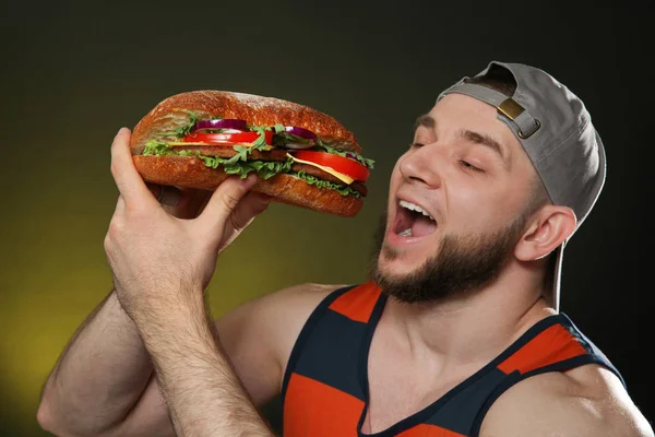 Mladý Muž Jíst Chutné Burger Barvu Pozadí — Stock fotografie