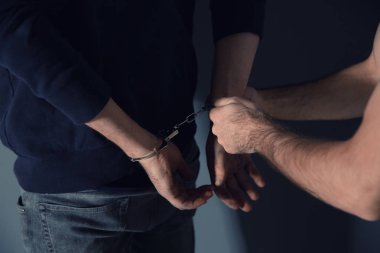 Man putting handcuffs on drug dealer, closeup view clipart