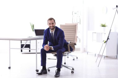 İşyerinde rahat ofis koltuğu oturan genç işadamı
