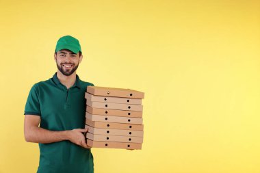 Genç kurye ile pizza kutuları üzerinde renk arka plan, metin için yer. Gıda dağıtım hizmeti