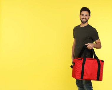 Renk arkaplanı termo çantalı genç kurye, mesaj için boşluk. Yemek dağıtım servisi.