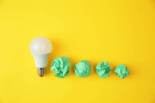 Flat lay composition with lamp bulb and crumpled paper on color background