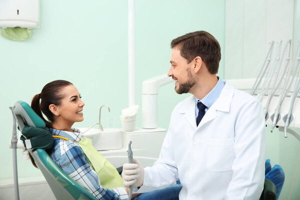 Professional dentist and happy patient in modern clinic