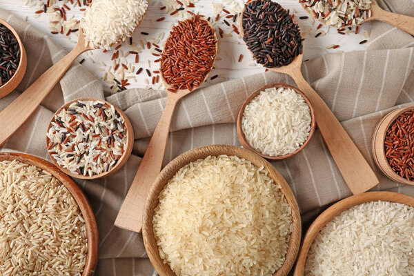 Flat lay composition with brown and other types of rice on wooden background
