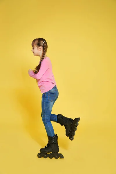 Girl with inline roller skates on color background