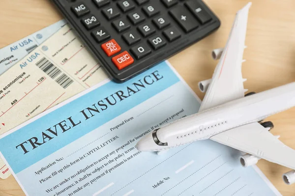 Composition with toy plane, calculator and travel insurance form on table