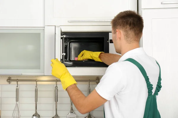 Αρσενικό Θυρωρών Που Καθαρίζουν Φούρνο Μικροκυμάτων Στην Κουζίνα — Φωτογραφία Αρχείου