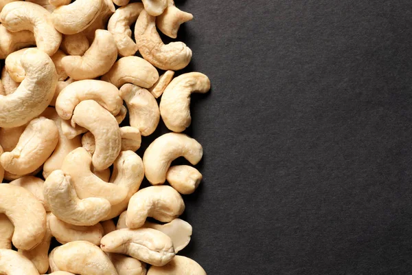 Tasty cashew nuts on black background, top view. Space for text