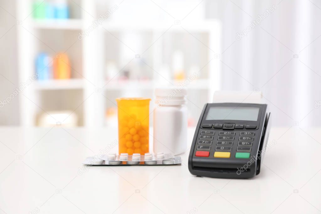 Payment terminal and pills on counter in pharmacy. Space for text