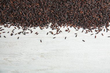 Üstten görünüm Beyaz ahşap arka plan üzerinde siyah pirinç pişmemiş. Metin için yer