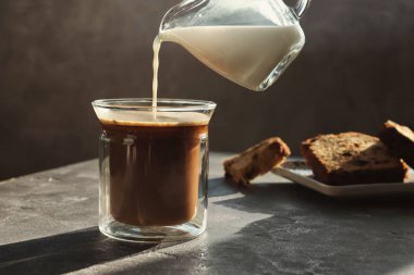 Sıcak gri masada aromatik kahve için süt ekleyerek. Metin için yer