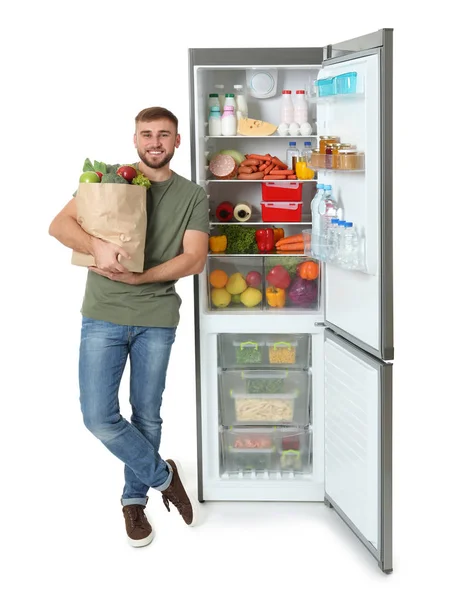 Молодой Человек Пакетом Продуктов Возле Открытого Холодильника Белом Фоне — стоковое фото