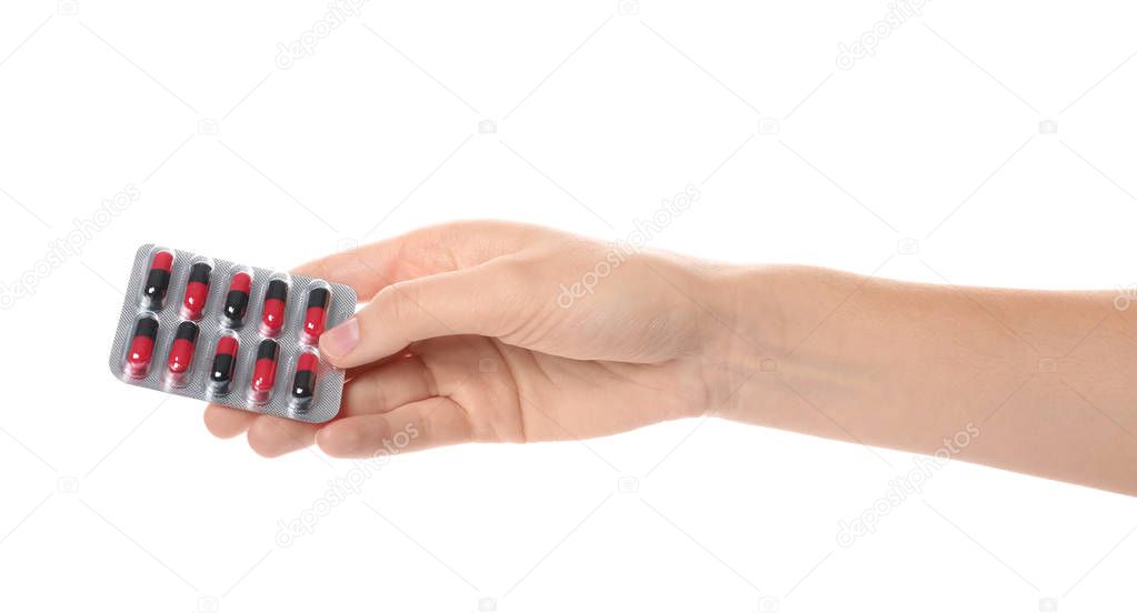 Woman holding pills in blister pack on white background, closeup
