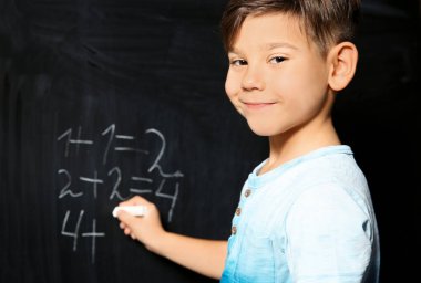 Mektup yazma ve matematik yeşil yazı tahtası üzerinde yapıyor küçük çocuk