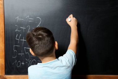 Blackboard matematikte yaparken tebeşir ile küçük çocuk