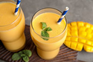 Gözlük taze mango içecek ve meyve masada, portre