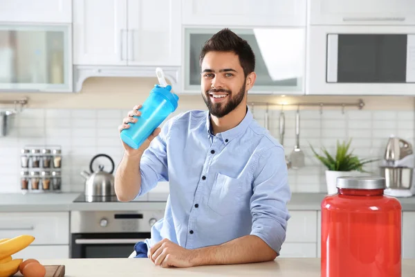 Молодий Чоловік Тримає Пляшку Білка Столом Інгредієнтами Кухні — стокове фото