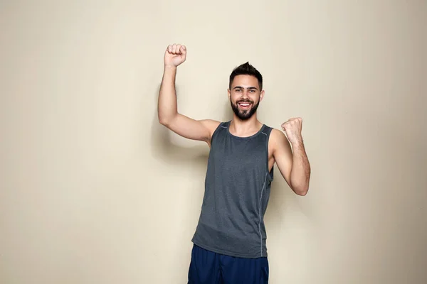 Happy young man celebrating victory on color background