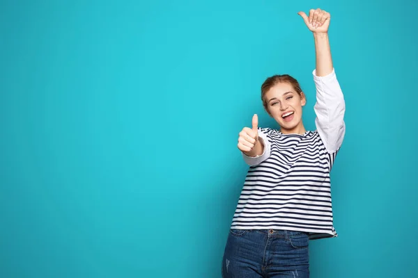 快乐的年轻女子在颜色背景上竖起大拇指 庆祝胜利 — 图库照片