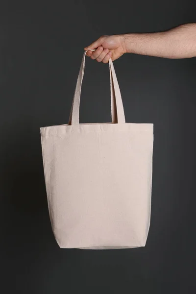 男子拿着棉购物袋在灰色的背景 用于设计的模型 — 图库照片