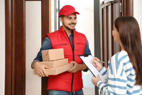 Woman receiving parcels from delivery service courier indoors