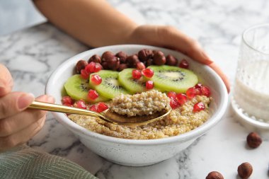 Fındık, kivi ve nar ile Quinoa yulaf lapası yemek kadın mermer masada, closeup tohum