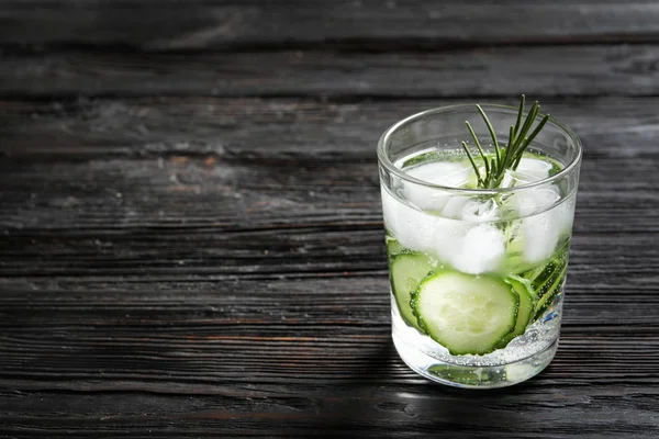 Glass of fresh cucumber water on wooden table. Space for text