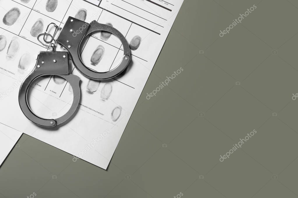 Police handcuffs and criminal fingerprints card on grey background. Space for text