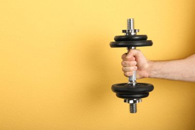Erkek atlet renk arka plan üzerinde metal dumbbell tutarak. Metin için yer
