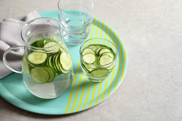 Glasses and jug of fresh cucumber water on table. Space for text