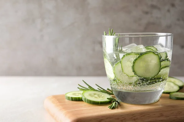 Glass of fresh cucumber water on table. Space for text