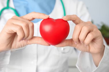 Doktor kırmızı kalbi tutuyor, yakın plan. Kardiyoloji kavramı